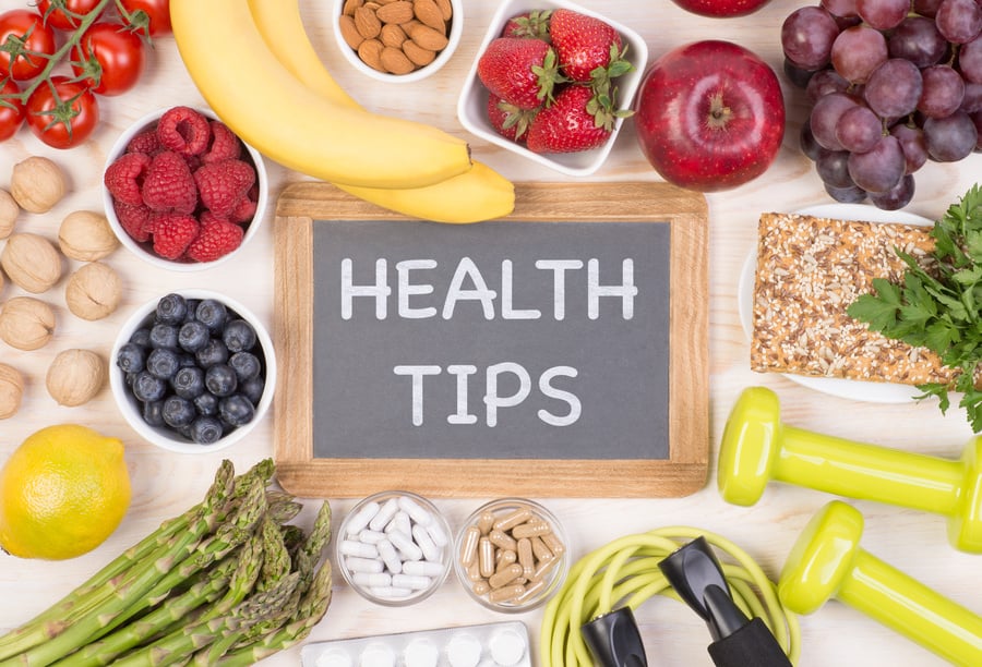 Phrase "Health Tips" written on a board surrounded by healthy food, medicine and fitness equipment